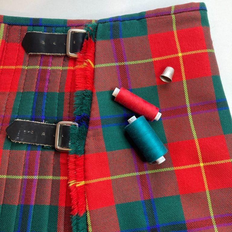 Kilt Alteration and Repairs - Glasgow Specialist kilt laid out with straps and sewing tools during alteration work